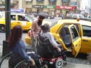 photo of two people in wheelchairs in front of a cab