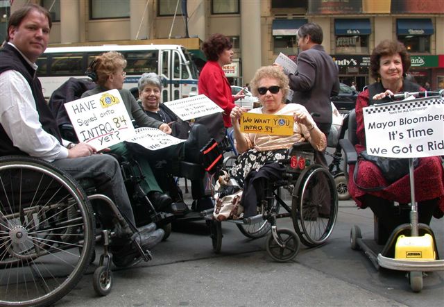 larger photo of people in wheelchairs holding signs