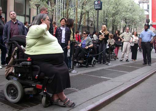 larger photo of people in wheelchairs and pedestrians at Penn Station taxi stand