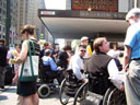photo of people in wheelchairs talking to reporters in front of Penn Station