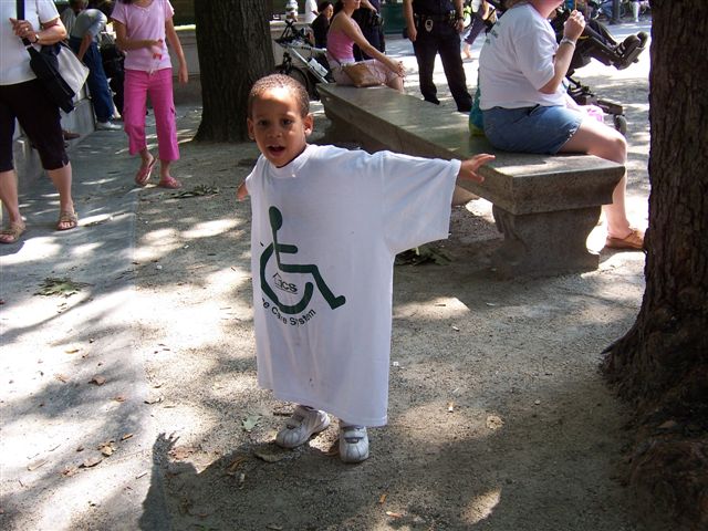 A young boy in an Independent Care Systems (ICS) T-shirt stretches his arms out wide.