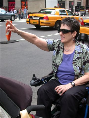 Jean Ryan from her wheelchair with right arm in the air