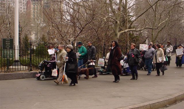 Protesters walk (and ride in wheelchairs and scooters) into City Hall Park heading to City Hall on March 13, 2003.