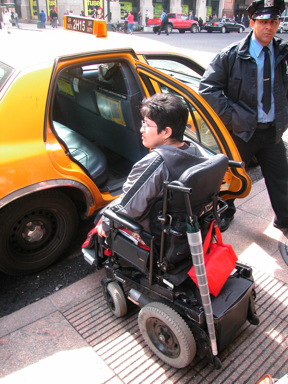 a woman in a wheelchair in front of an open taxi door